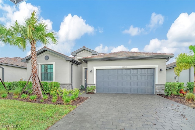 single story home with stone siding, decorative driveway, an attached garage, and stucco siding