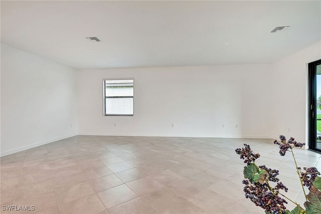 empty room featuring light tile patterned floors, baseboards, and visible vents