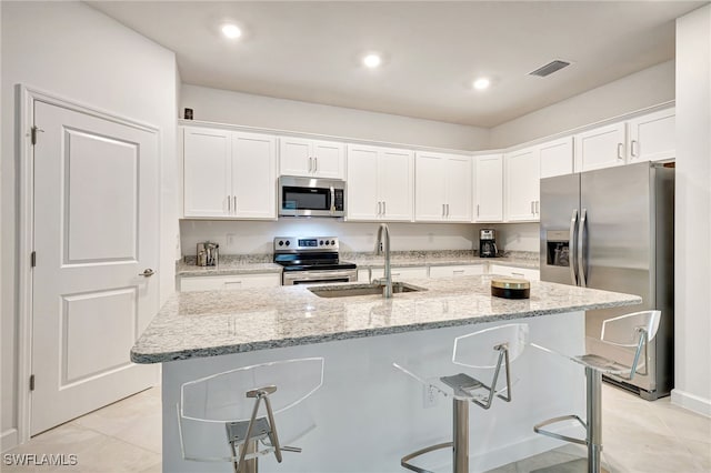 kitchen with visible vents, appliances with stainless steel finishes, white cabinets, a sink, and a kitchen breakfast bar