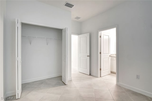 unfurnished bedroom featuring a closet, visible vents, connected bathroom, and light tile patterned flooring