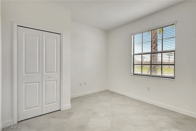 unfurnished bedroom with a closet and baseboards