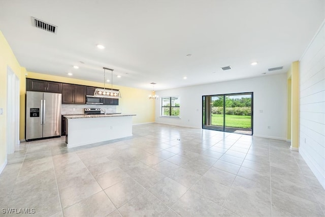 kitchen featuring light stone countertops, appliances with stainless steel finishes, a kitchen island, dark brown cabinetry, and pendant lighting