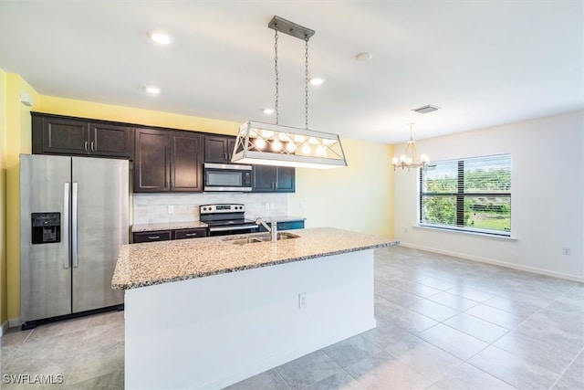 kitchen with an island with sink, dark brown cabinets, sink, pendant lighting, and appliances with stainless steel finishes