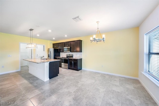 kitchen with decorative light fixtures, stainless steel appliances, a center island with sink, and sink