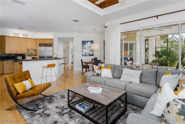 living room featuring visible vents, light wood-style flooring, and a ceiling fan