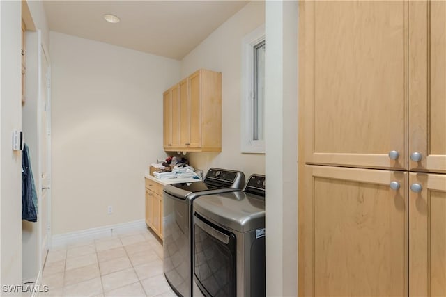 laundry area featuring cabinet space, washing machine and dryer, light tile patterned floors, and baseboards