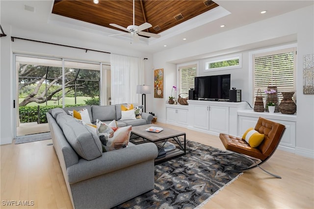 living area featuring light wood finished floors, wood ceiling, a raised ceiling, and a wealth of natural light