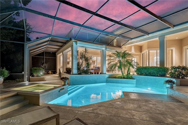 outdoor pool featuring glass enclosure, a patio, and an in ground hot tub