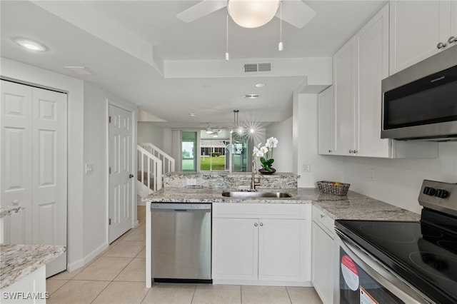 kitchen featuring stainless steel appliances, white cabinetry, sink, light stone countertops, and kitchen peninsula