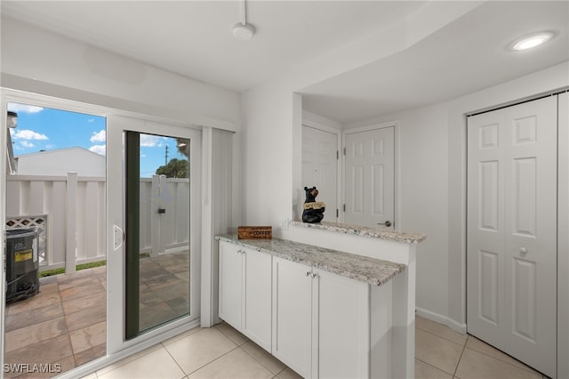 kitchen featuring light stone counters, white cabinetry, and light tile patterned floors