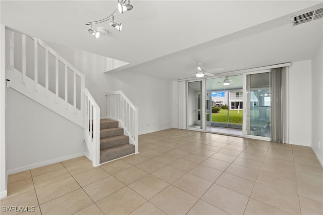 spare room featuring light tile patterned floors, visible vents, baseboards, and stairway