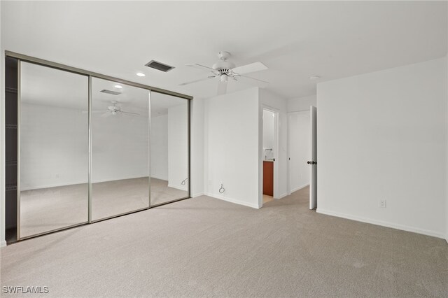 unfurnished bedroom featuring ceiling fan, light colored carpet, and a closet