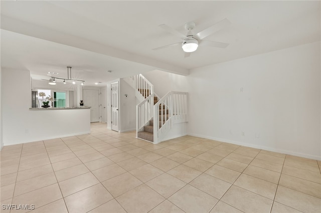 unfurnished room with light tile patterned flooring, baseboards, ceiling fan, and stairs