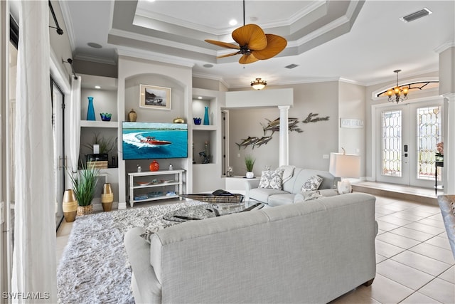 living room with light tile patterned flooring, ornamental molding, and a tray ceiling