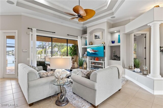 living room featuring ornate columns, ceiling fan, a tray ceiling, light tile patterned floors, and crown molding