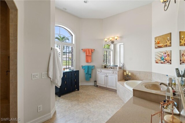 bathroom with tiled bath, vanity, and tile patterned floors