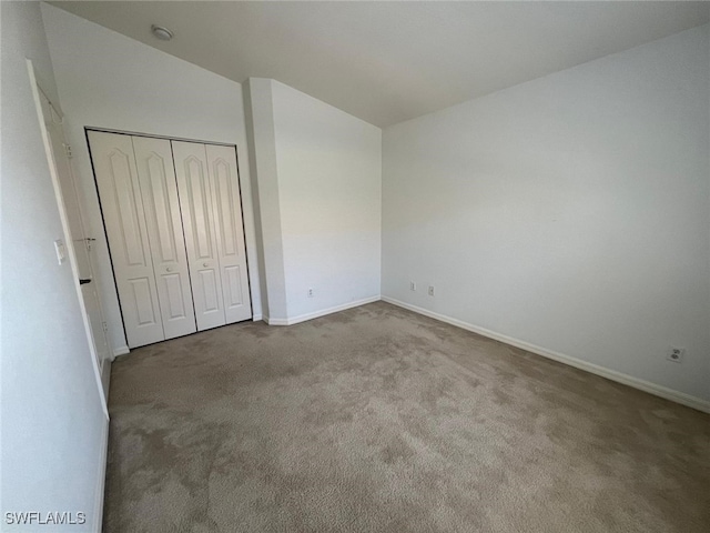 unfurnished bedroom with lofted ceiling, light colored carpet, and a closet