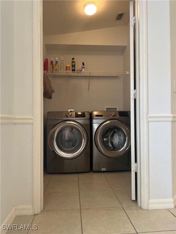 laundry room with independent washer and dryer and light tile patterned floors