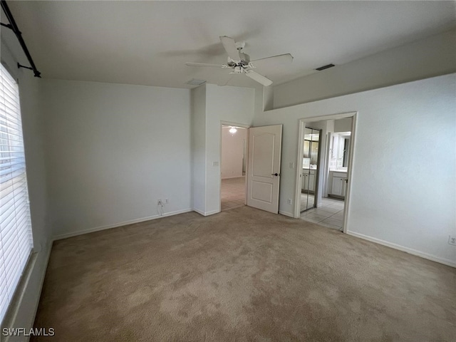 unfurnished bedroom featuring ceiling fan, ensuite bath, and light carpet