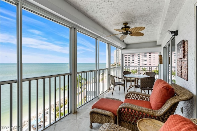 sunroom featuring ceiling fan and a water view