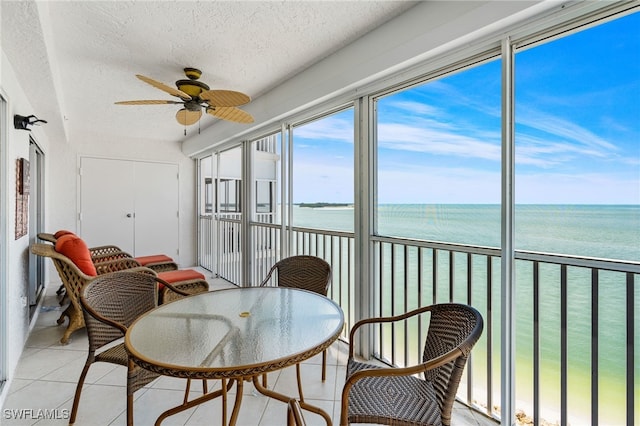 sunroom / solarium with ceiling fan and a water view