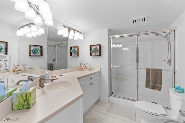 bathroom featuring a shower with door, vanity, and toilet