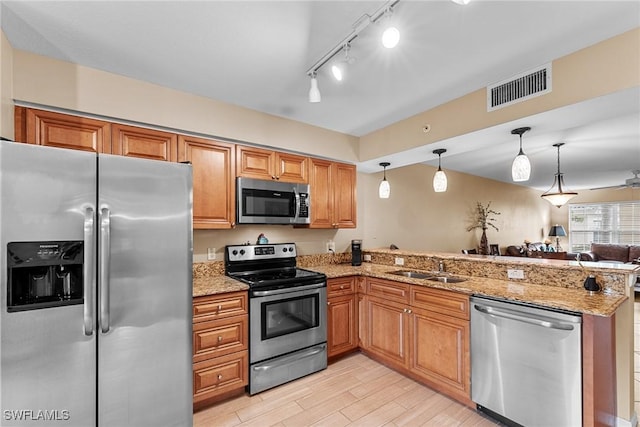 4965 Sandra Bay Dr Unit 103, Naples, FL 34109 - kitchen featuring stainless steel appliances, a peninsula, light stone counters, light wood finished floors, and decorative light fixtures