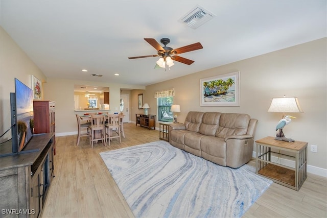 living room with light hardwood / wood-style flooring and ceiling fan