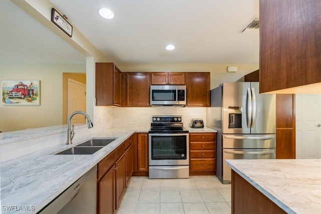 kitchen featuring light stone counters, sink, appliances with stainless steel finishes, and tasteful backsplash