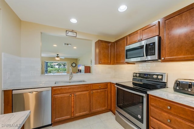 kitchen featuring light tile patterned floors, tasteful backsplash, stainless steel appliances, sink, and ceiling fan