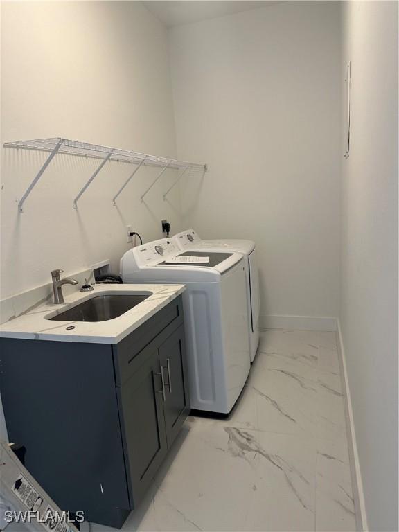 washroom with cabinets, washing machine and dryer, and sink