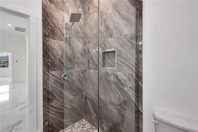 bathroom featuring tiled shower and toilet