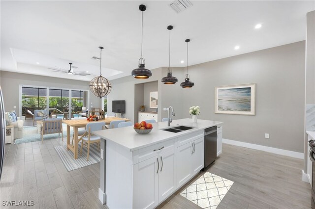 kitchen with stainless steel dishwasher, a kitchen island with sink, sink, light hardwood / wood-style flooring, and white cabinets