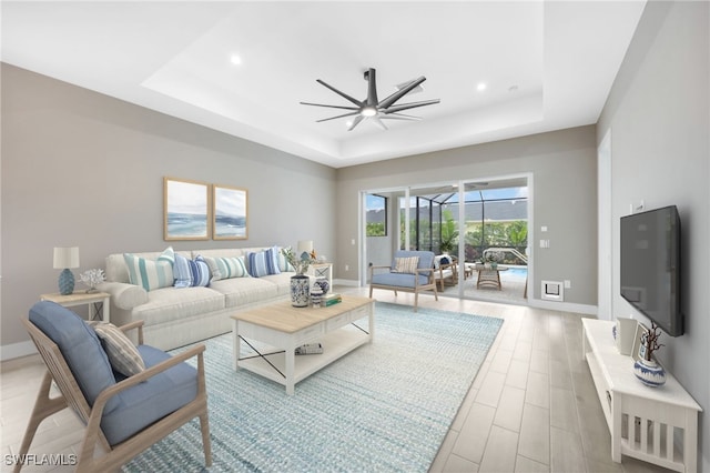 living room with ceiling fan and a tray ceiling