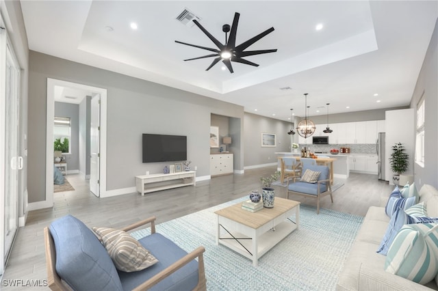 living room featuring light wood-type flooring and a tray ceiling