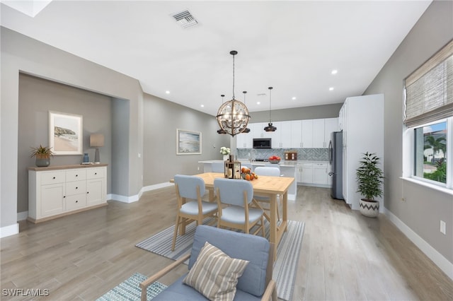 dining space featuring light hardwood / wood-style floors and a chandelier