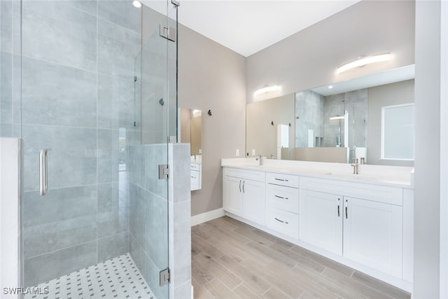 bathroom featuring a shower with door and vanity