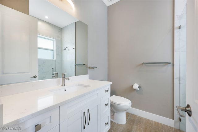 bathroom with toilet, vanity, a shower with shower door, and hardwood / wood-style flooring