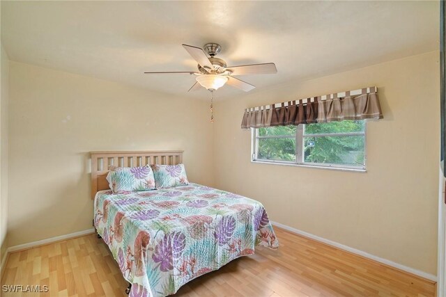 bedroom with a ceiling fan, baseboards, and wood finished floors