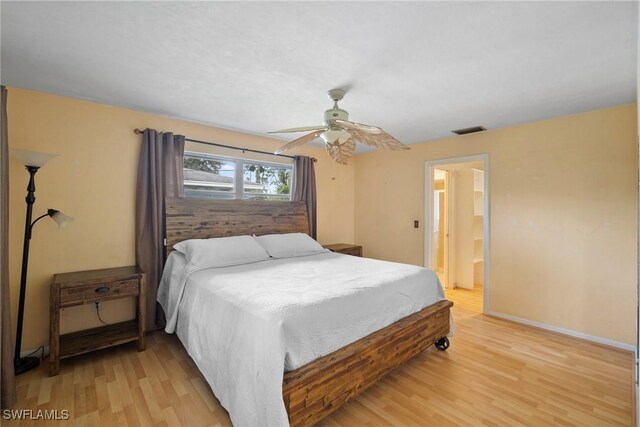 bedroom featuring baseboards, visible vents, a ceiling fan, ensuite bath, and light wood-style floors