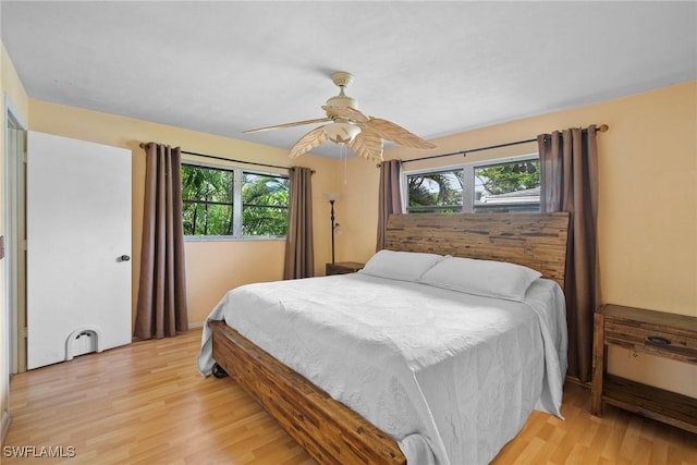 bedroom with multiple windows, ceiling fan, and light wood-style flooring