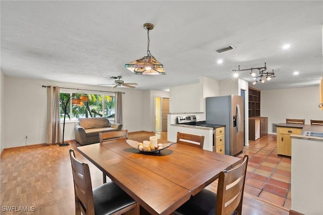 dining space with baseboards, visible vents, ceiling fan, and light wood-style flooring