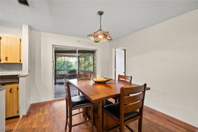 dining space with baseboards, visible vents, and light wood finished floors