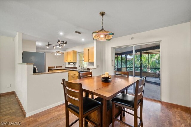 dining area featuring light wood finished floors, baseboards, and visible vents