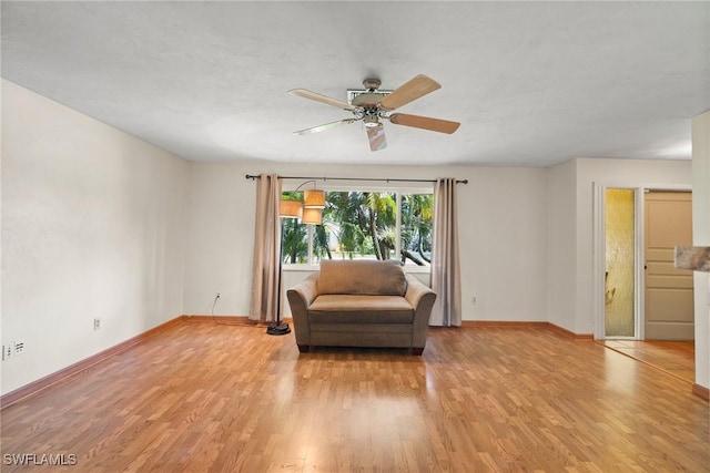 sitting room with baseboards, ceiling fan, and light wood finished floors