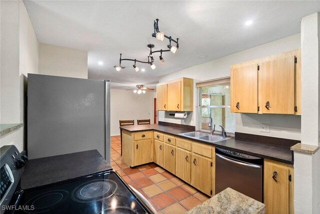 kitchen featuring dark countertops, a peninsula, appliances with stainless steel finishes, and a sink