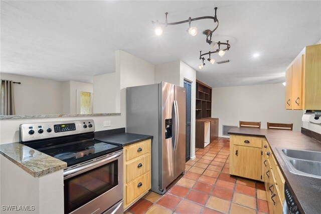 kitchen with stainless steel appliances, dark countertops, light brown cabinets, light tile patterned flooring, and a peninsula