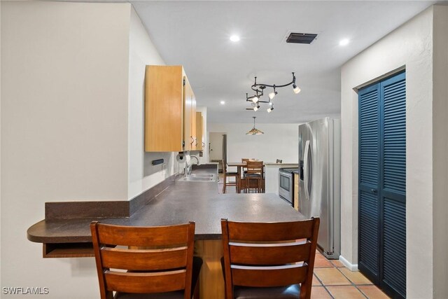 kitchen featuring light tile patterned floors, visible vents, appliances with stainless steel finishes, a peninsula, and a sink