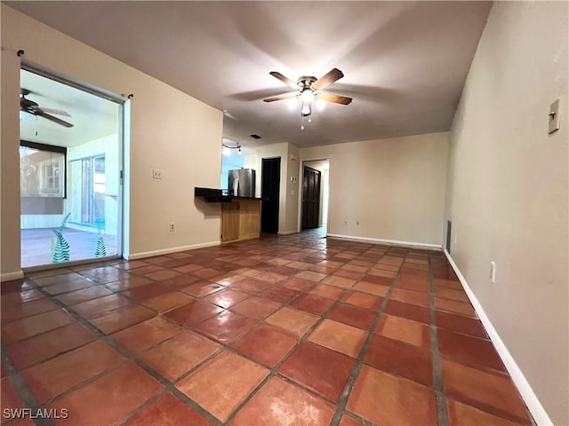 unfurnished living room with a ceiling fan, tile patterned flooring, and baseboards