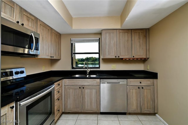 kitchen featuring sink, stainless steel appliances, a raised ceiling, and light tile patterned flooring